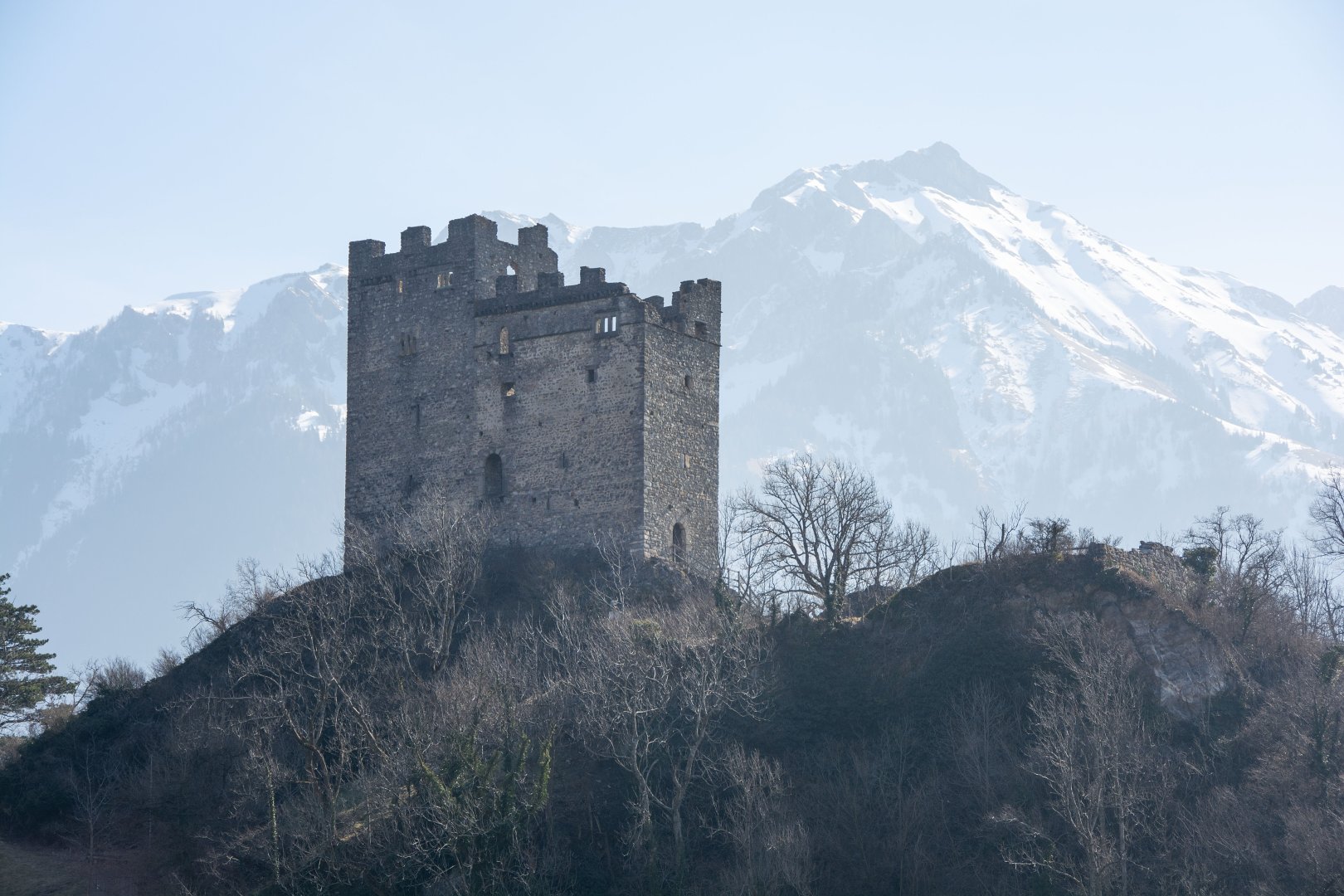 Ruins of a castle in front of a mountain range background.